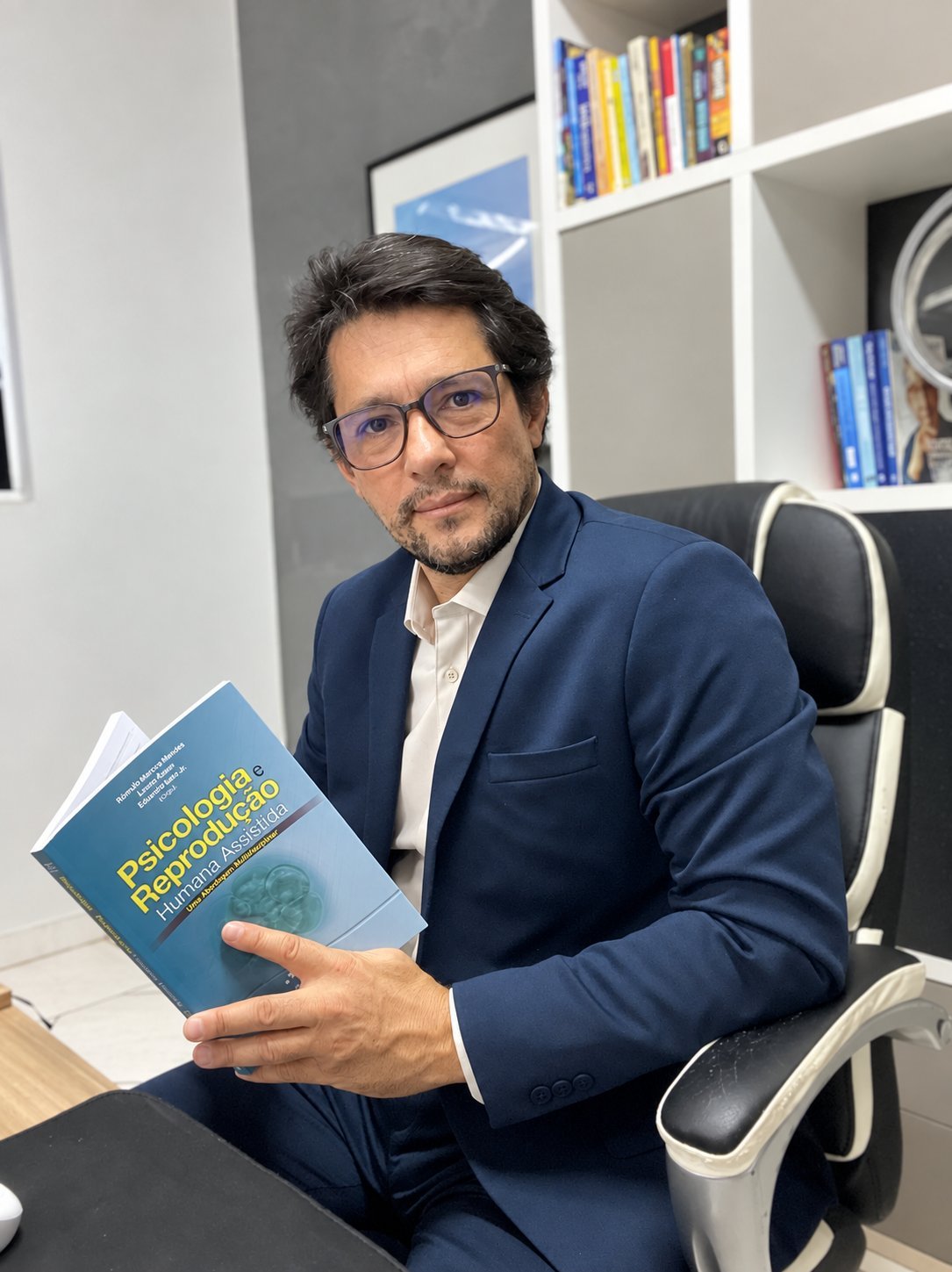 Cesar Coutinho, psicólogo clínico em Indaiatuba — de terno azul, com um livro de psicologia no escritório — CRP 06/223499